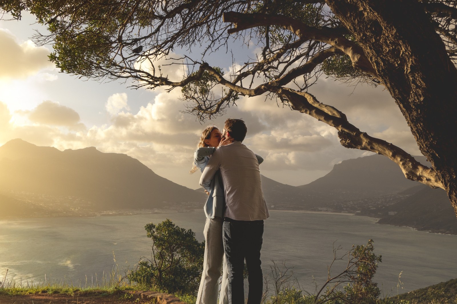 Couple embracing beneath a broad tree above the Atlantic coastline