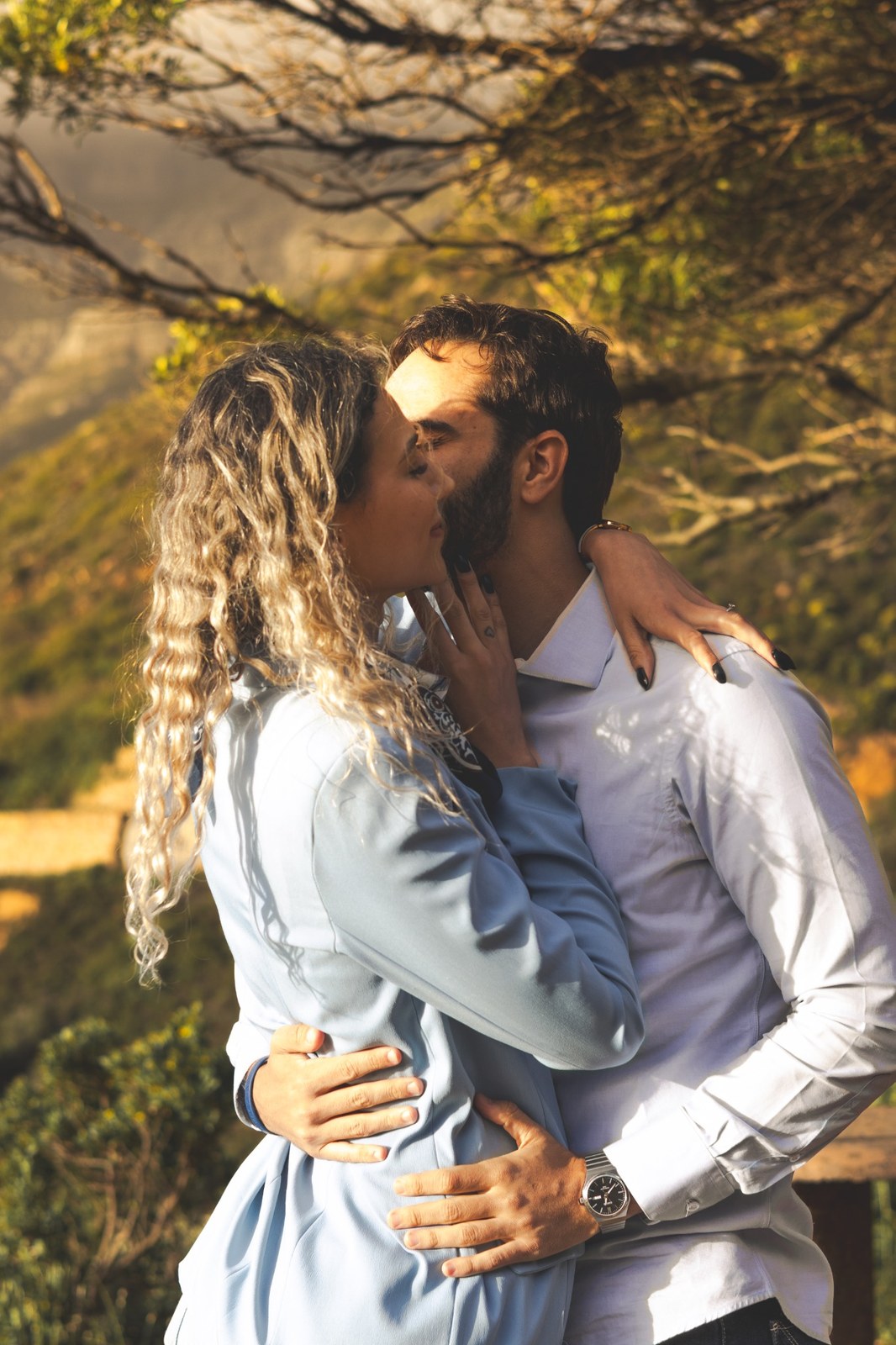 Close portrait of the couple kissing beneath sunlit branches