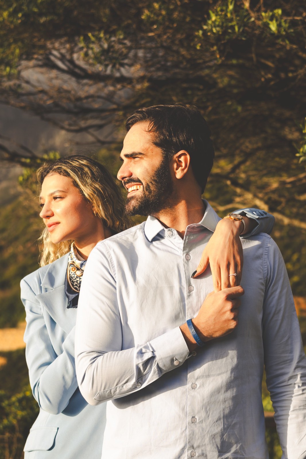 Woman resting her arm across her partner’s shoulders as they look toward the coast