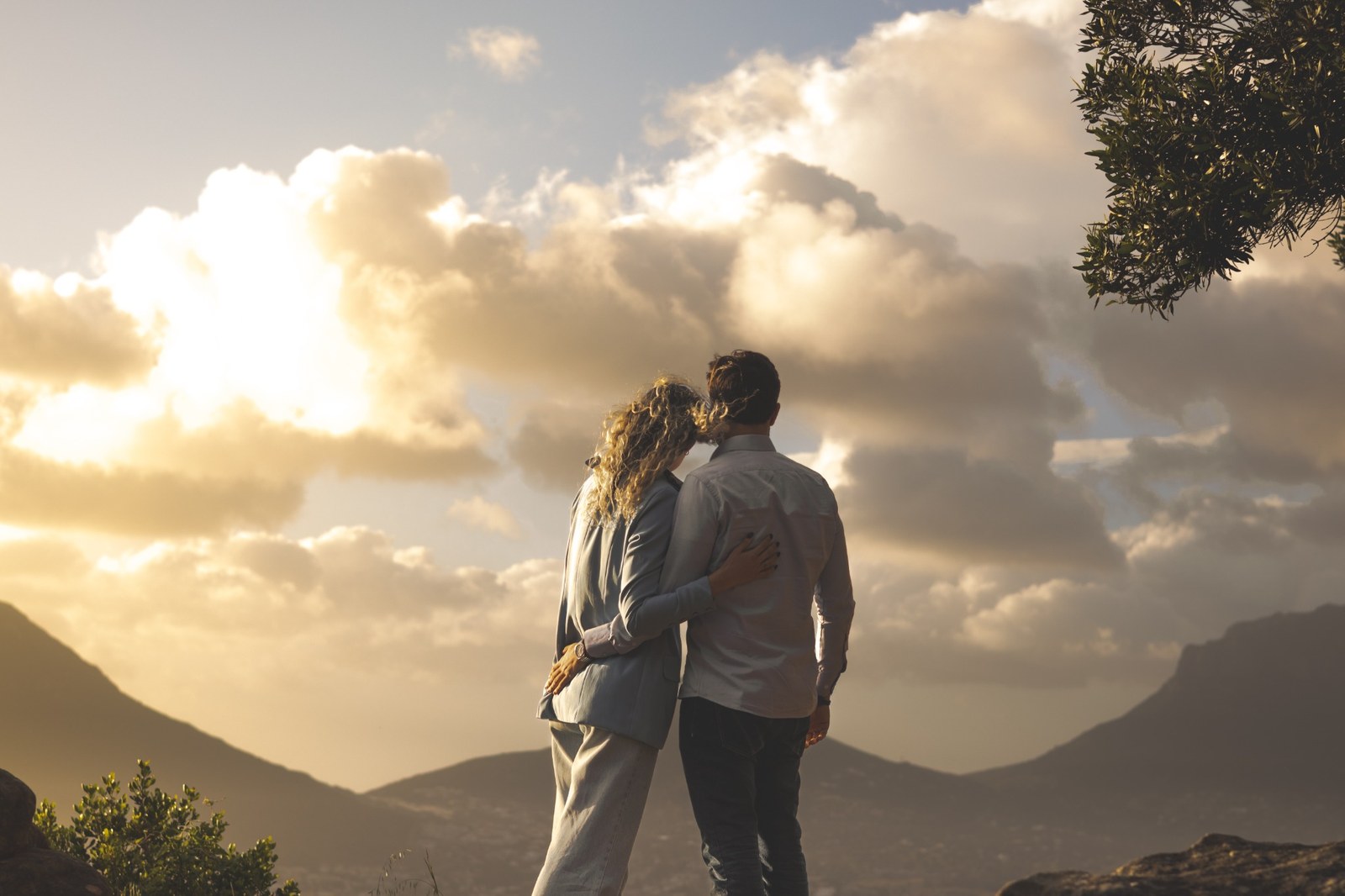 Couple seen from behind looking toward clouds over the mountains