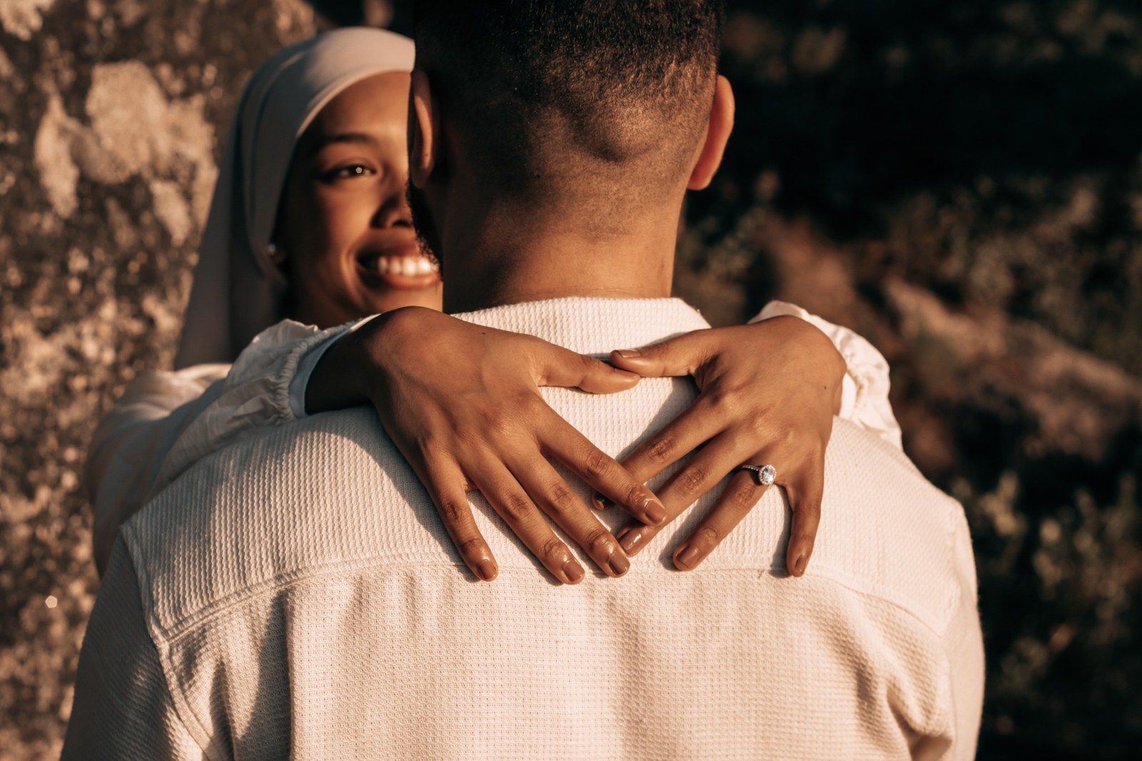 Woman smiling as she embraces her partner, with her engagement ring visible