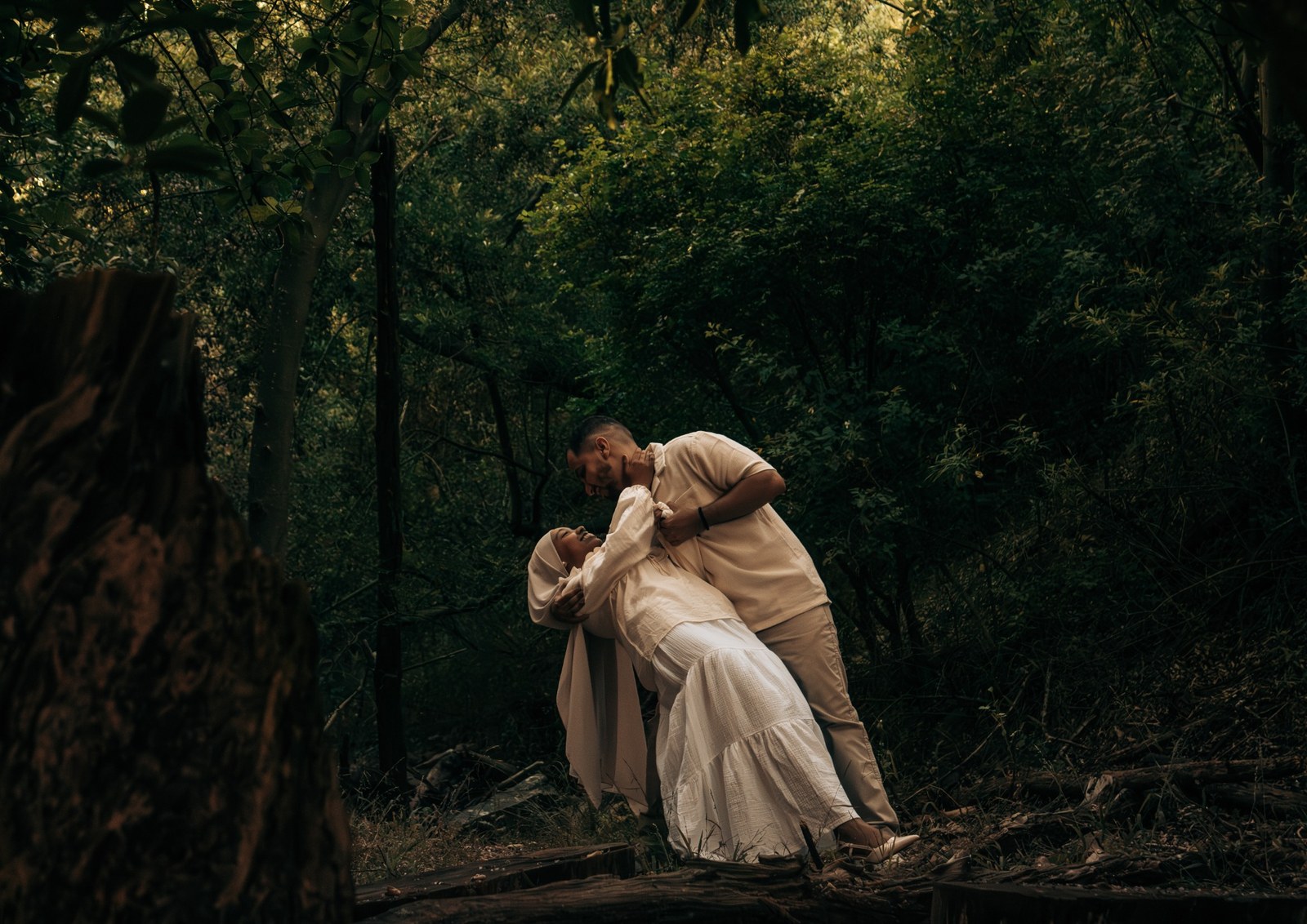 Man dipping his partner into an embrace along a shaded forest path