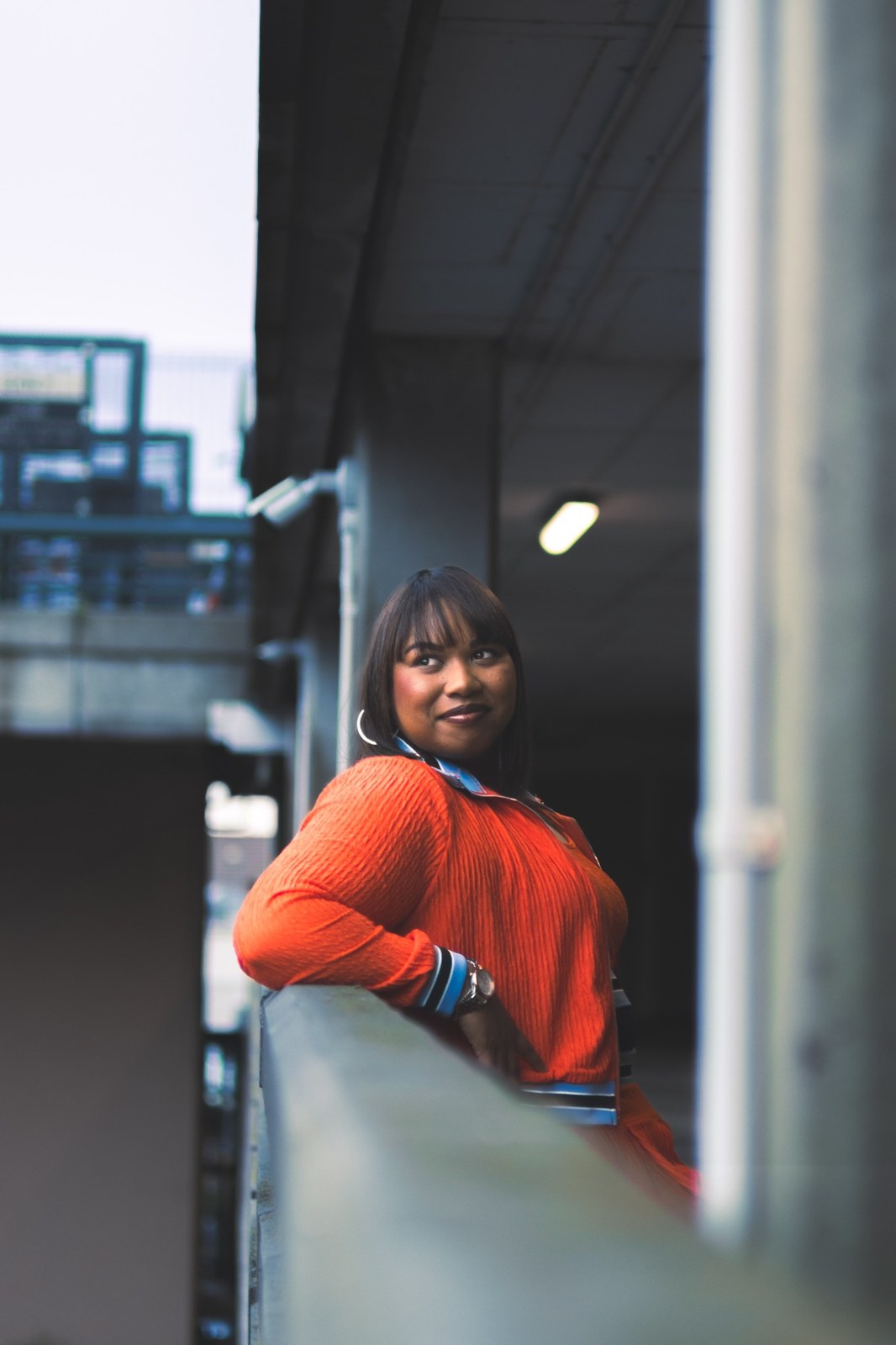 Woman leaning on a concrete wall and looking back toward the camera