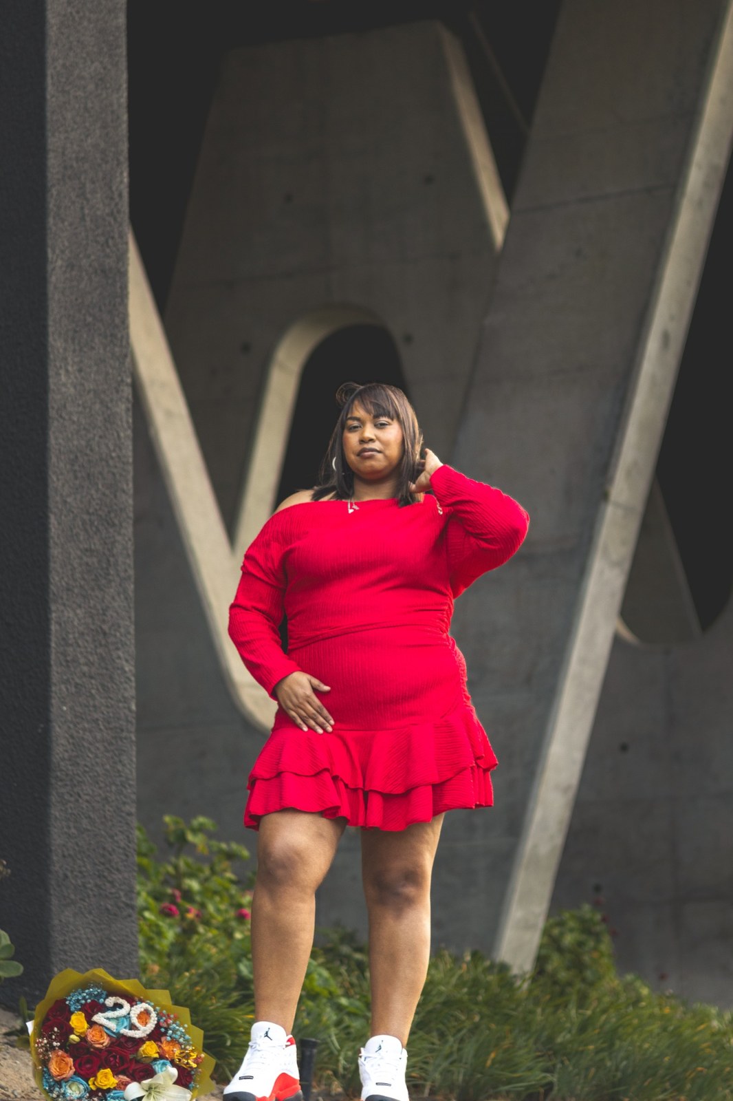 Woman in a red dress beneath angled concrete supports