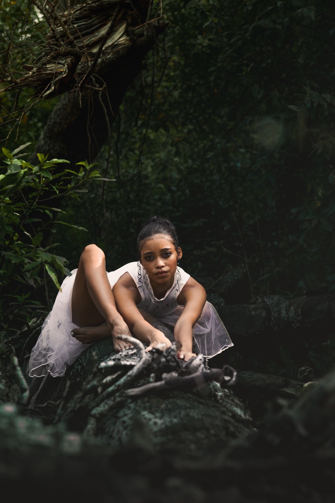Woman leaning forward over a moss-covered rock with both hands outstretched
