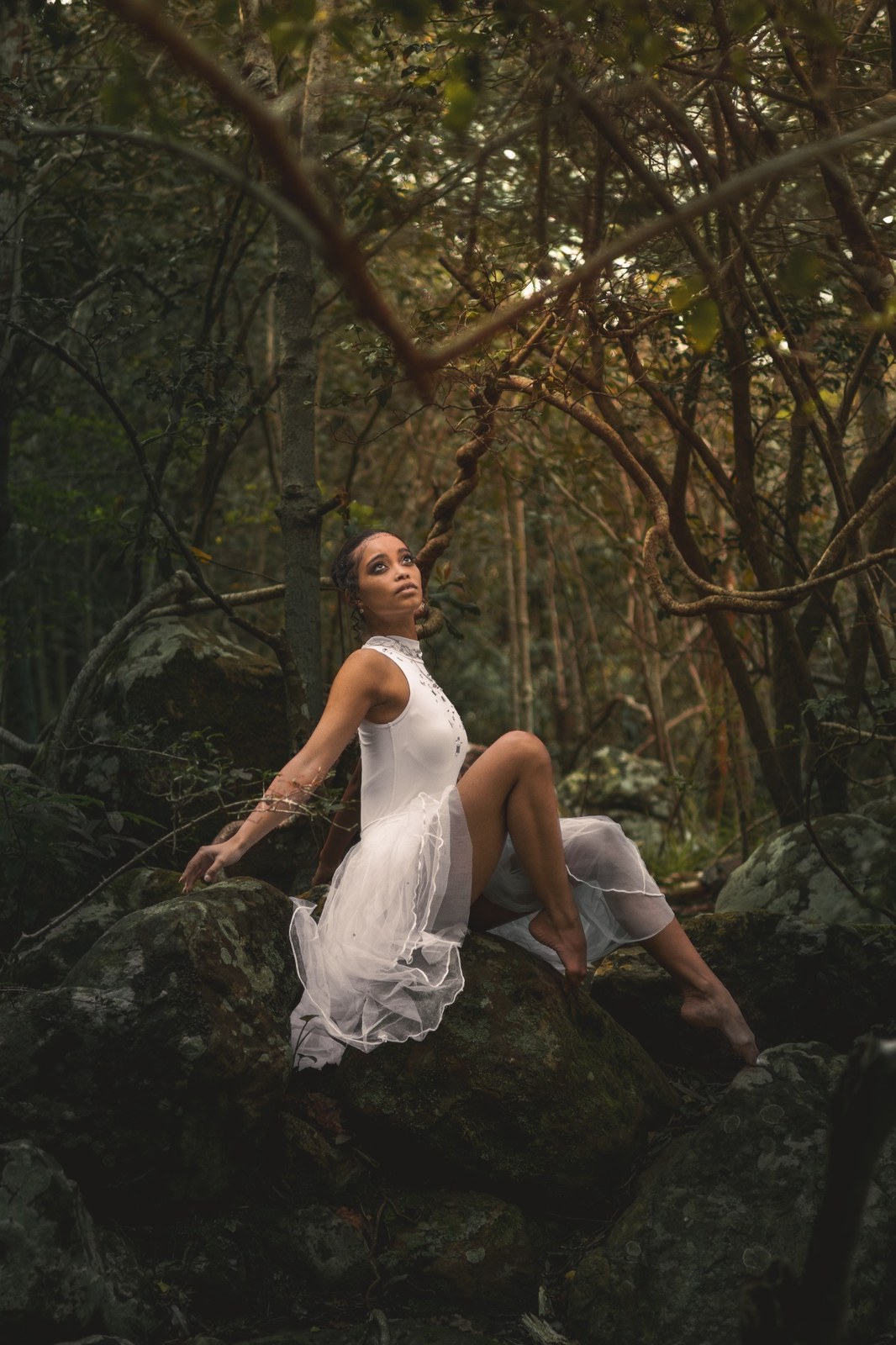 Woman resting on a mossy rock with one knee raised
