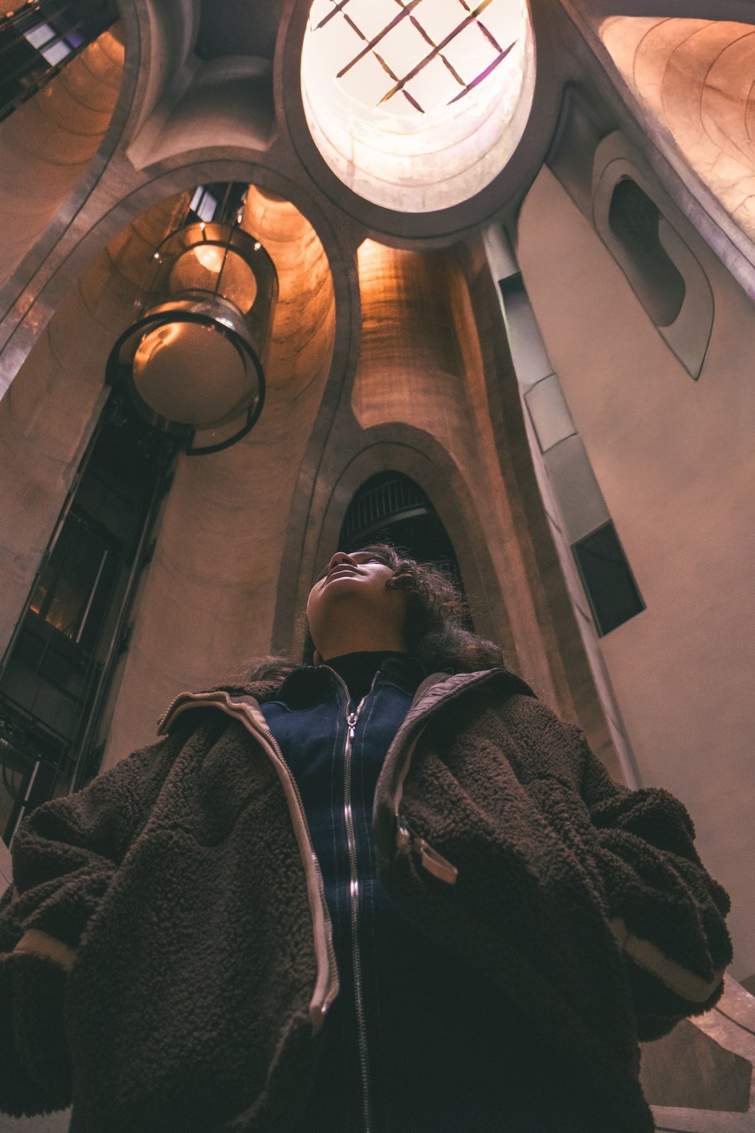 Low-angle portrait of a woman beneath the museum’s curved concrete atrium
