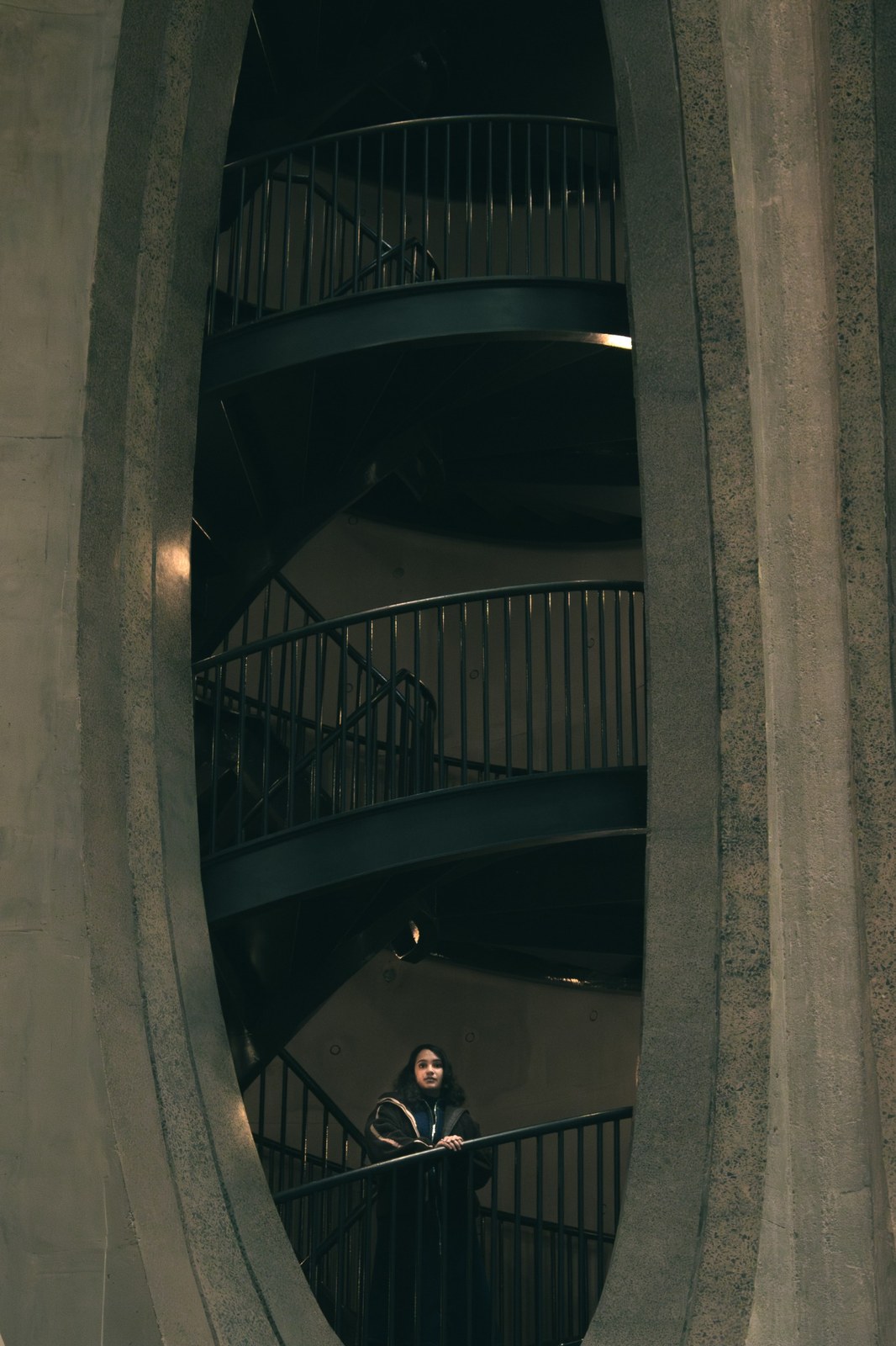 Distant portrait of a woman on a staircase inside a tall concrete opening